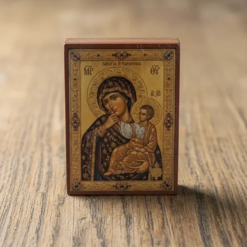 Close up of a handmade Panagia Paramythia Orthodox wooden mounted icon on a natural wood surface.